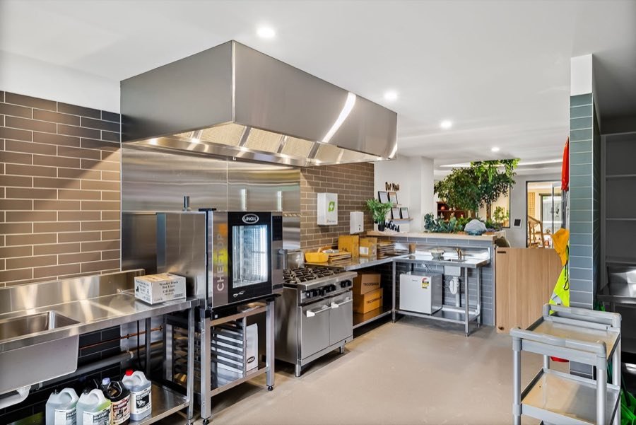 Stainless steel commercial kitchen with a large range hood